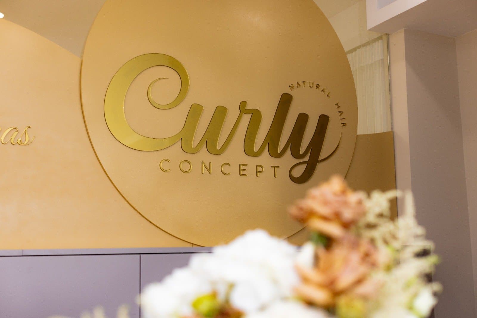 Logótipo dourado da Curly Concept na parede do salão